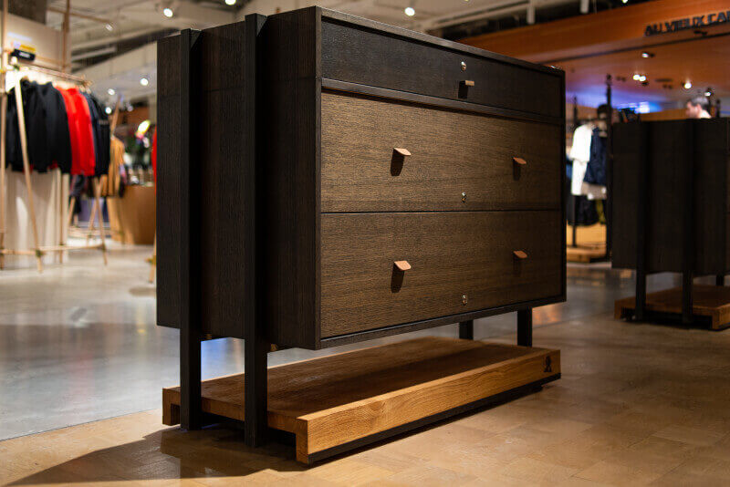 Wooden merchandise storage with drawers finished in a dark wood finish.