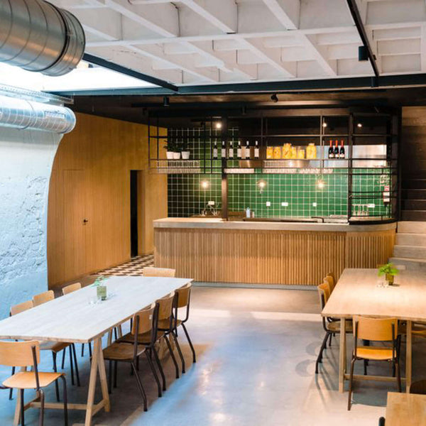 A view from the front of the event space features tables and chairs in the foreground and a flue bar in the background.