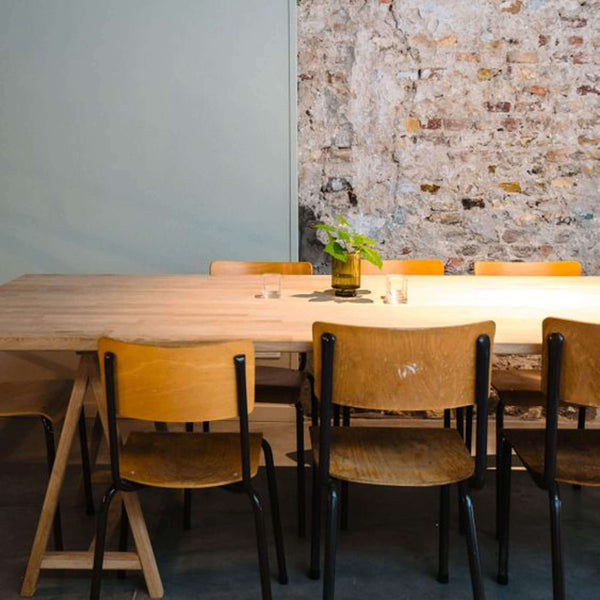 A table finished with Rubio Monocoat Oil Plus 2C and chairs are in the foreground. The table is adorned with a plant and other decorations.