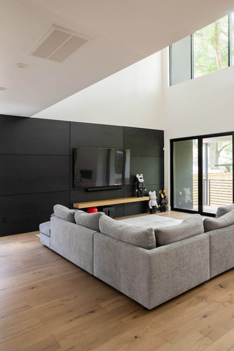 An angled shot of a modern chippendale living room which features a black wood wall finished in rubio monocoat products.