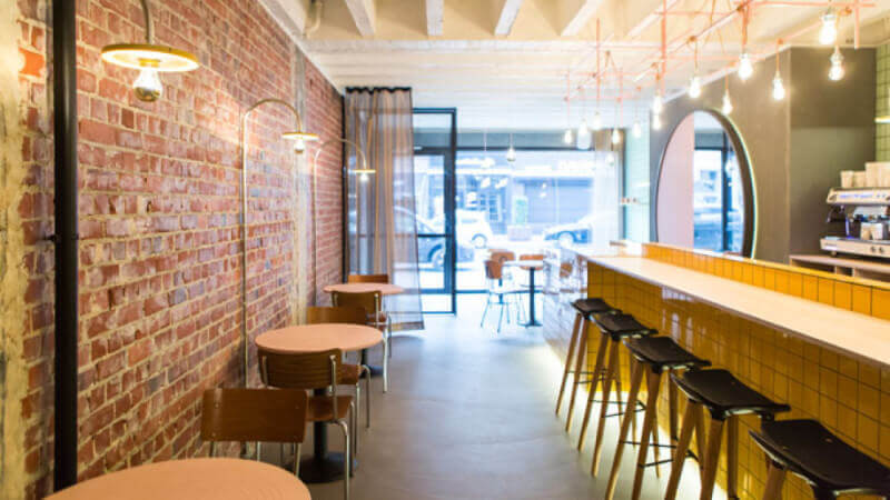 The inside of a long but small restaurant with bright color wood surfaces.