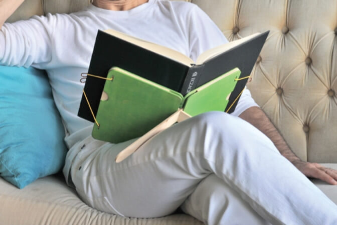Man sitting on couch using a book saddle.