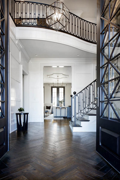 Entryway with herringbone wood flooring with a dark floor finish on them.