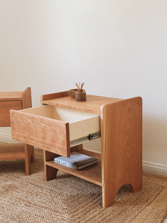 Solid cherry nightstand with drawer open revealing dovetail box construction and soft-close slides, Rubio Monocoat Oil Plus 2C Pure finish, styled with book and diffuse