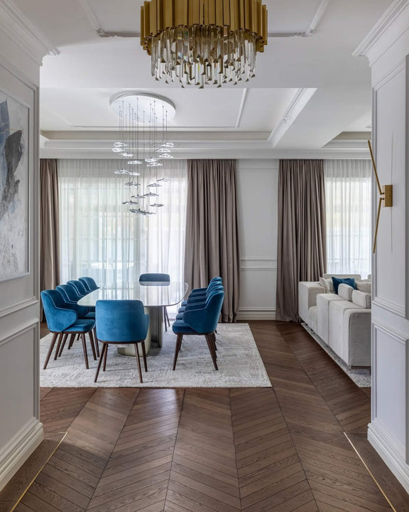 Formal dining room with white oak chevron parquet finished in Rubio Monocoat Oil Plus 2C hardwax oil, an oval dining table surrounded by teal velvet chairs, and layered statement chandeliers overhead.