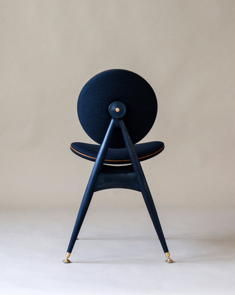 A blue, wood dining chair with brass, leather and fabric accents.