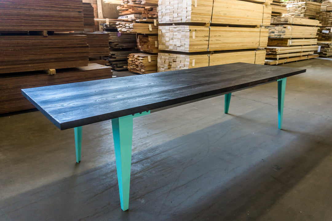 White oak dining table with blue metal legs.