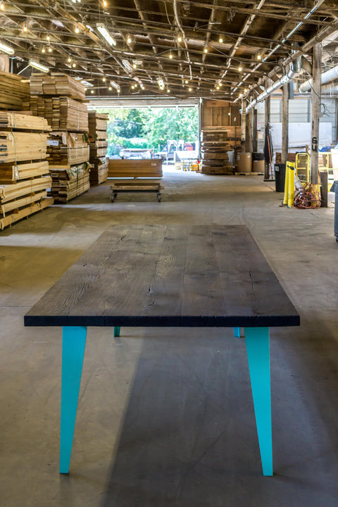 A charred white oak dining table with blue metal legs finished with Rubio Monocoat Oil Plus 2C "Pure".