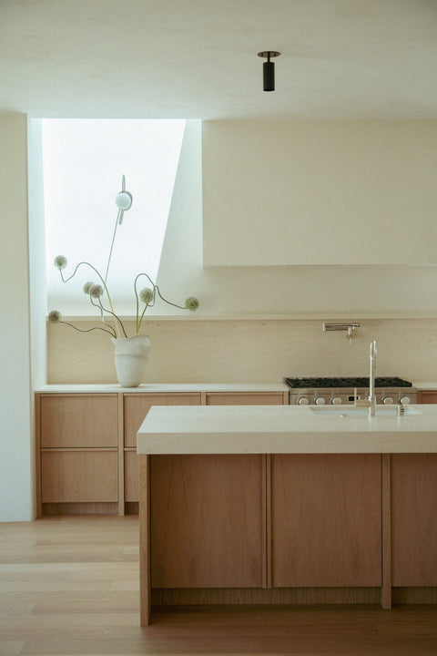 White oak kitchen island and cabinetry finished with Rubio Monocoat Oil Plus 2C Natural hardwax oil, paired with a stainless range and skylight nook.