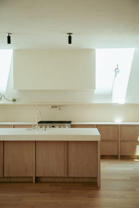 White oak island cabinetry in Rubio Monocoat Oil Plus 2C Natural hardwax oil finish, viewed toward the range wall and sculptural plaster hood.