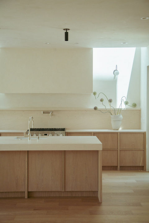 White oak kitchen cabinetry with Rubio Monocoat Oil Plus 2C Natural finish, island sink and range in view beneath a light-filled skylight.