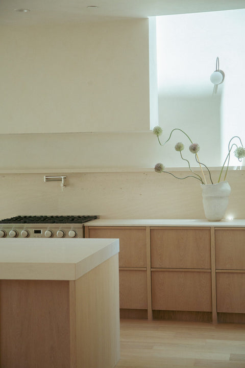 Detail of white oak lower cabinetry and island edge finished with Rubio Monocoat Oil Plus 2C Natural, alongside a pot filler and gas range.