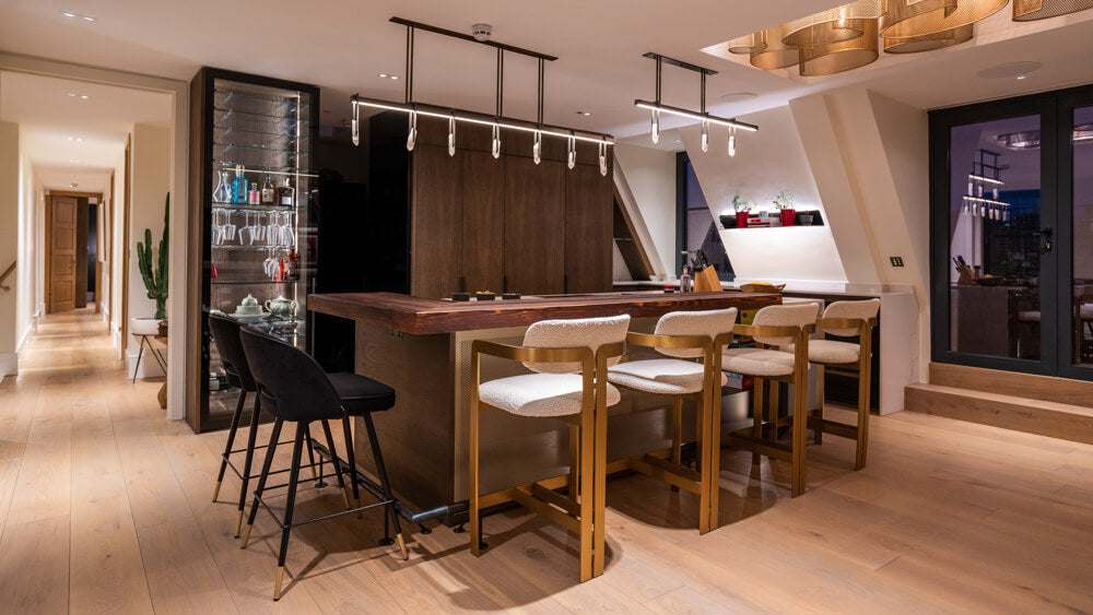 A diagonal shot of a modern kitchen complete with a raise wood bar top on this island.