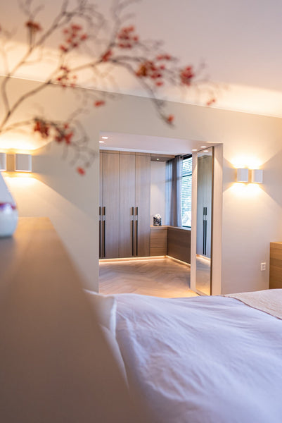A plant is out of focus in the foreground, while oak veneered closet doors are the primary focus in the background.
