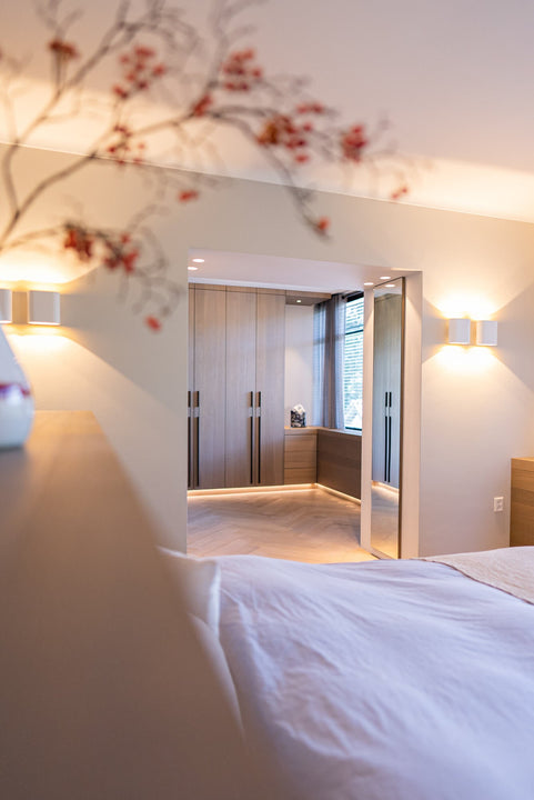 A plant is out of focus in the foreground, while oak veneered closet doors are the primary focus in the background.