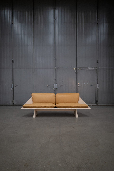 Leather cushions are placed on an ash sofa crafted from ash wood and finished using Rubio Monocoat Oil Plus 2C hardwax oil wood stain and finish.