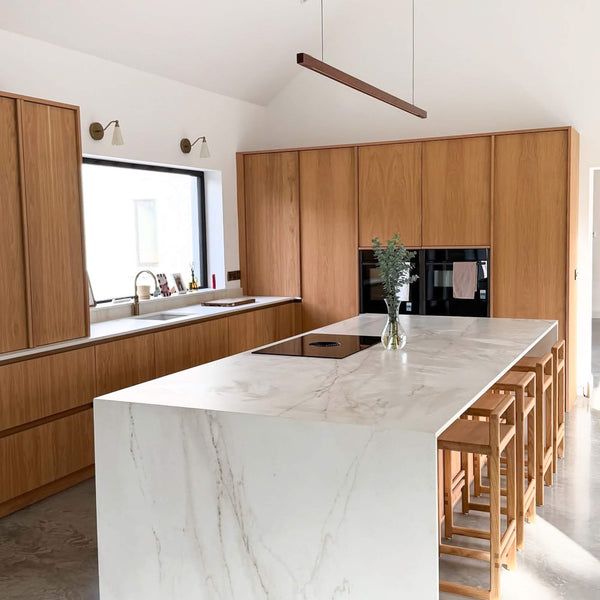 A modern kitchen featuring brass accents and wood finished with Rubio Monocoat Oil Plus 2C "Smoke 5%".