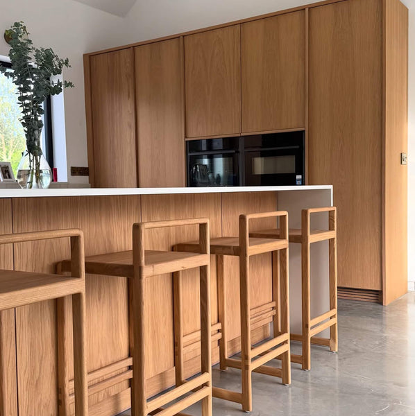 Oak cabinetry and barstools in a modern kitchen.