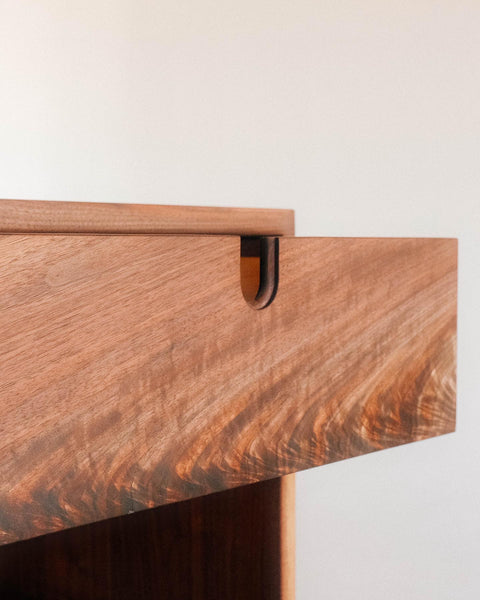 A close up of a side table's drawer with an integrated drawer pull.