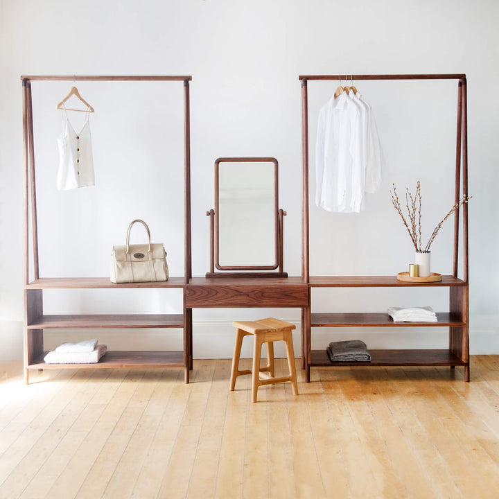 Two open wardrobe racks with a center vanity portion. Various items are displayed on the wardrobe rack.