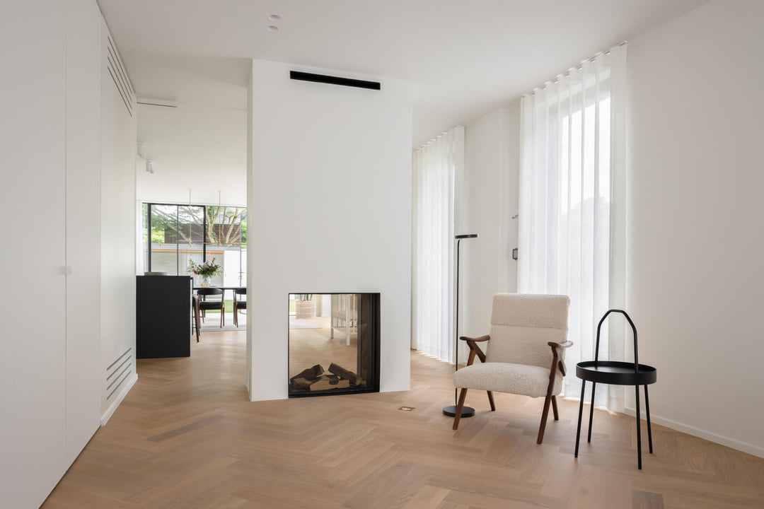 A plaster double sided fireplace in a living room with beautiful light-colored oak hardwood flooring.