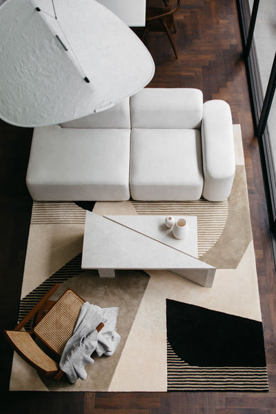 Looking down at a living area with a modern white sofa, light-colored coffee table and wood and cane accent chair.