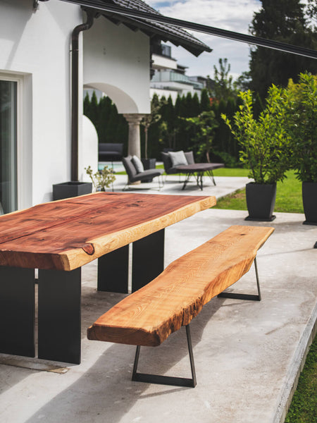 An outdoor redwood dining table on a garden patio.