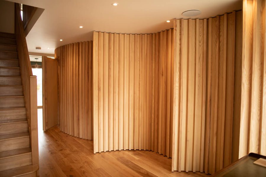 Curved millwork wall with hidden storage finished with a hardwax oil wood finish.