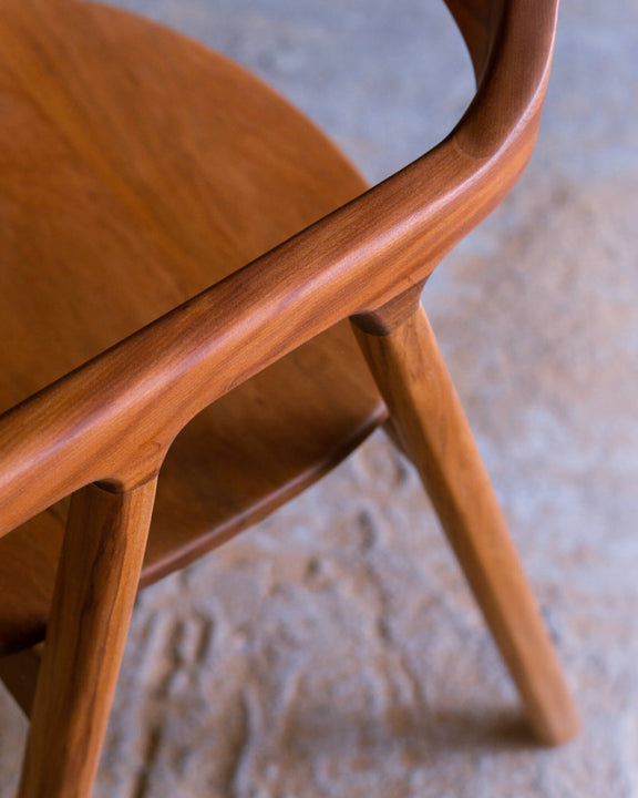 Side view of a walnut chair showing the armrest flowing into the seat and angled leg joinery.