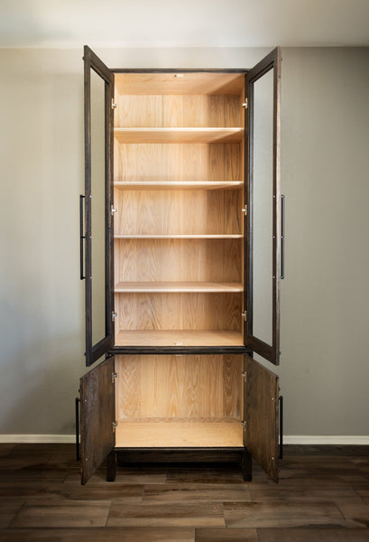 A red oak bookcase with its doors open, featuring a contrasting two-toned finish.