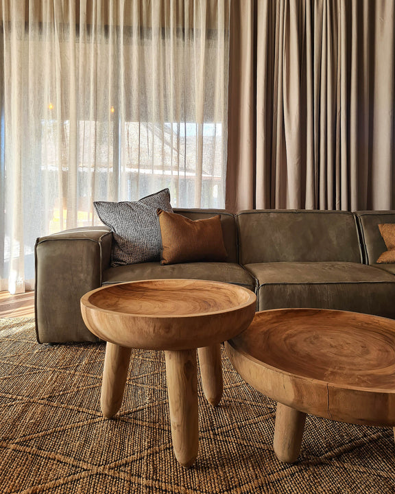 Two asymmetrical tables and a modern couch in a living room.