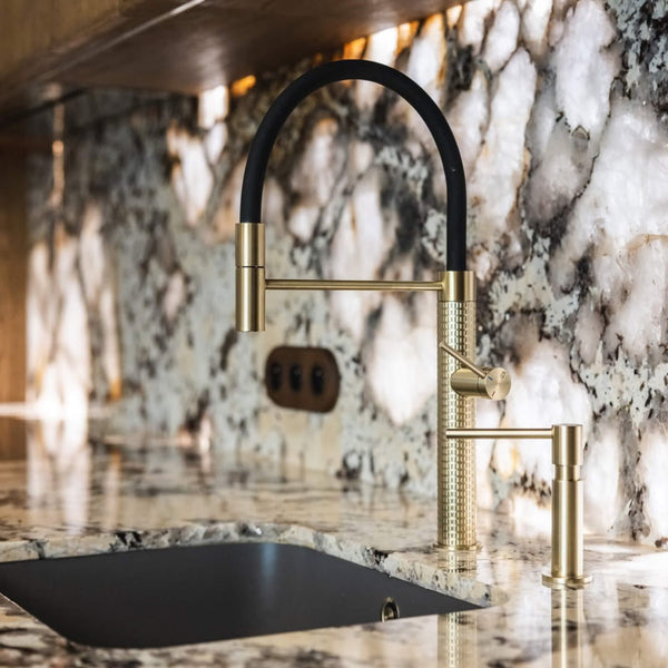 A modern faucet with brass detail in a warm minimalist kitchen.