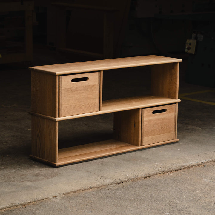 Angled view of a modern white oak modular bookcase with two open shelving cubbies and two removable storage cube drawers, finished with Rubio Monocoat Dunes hardwax oil.