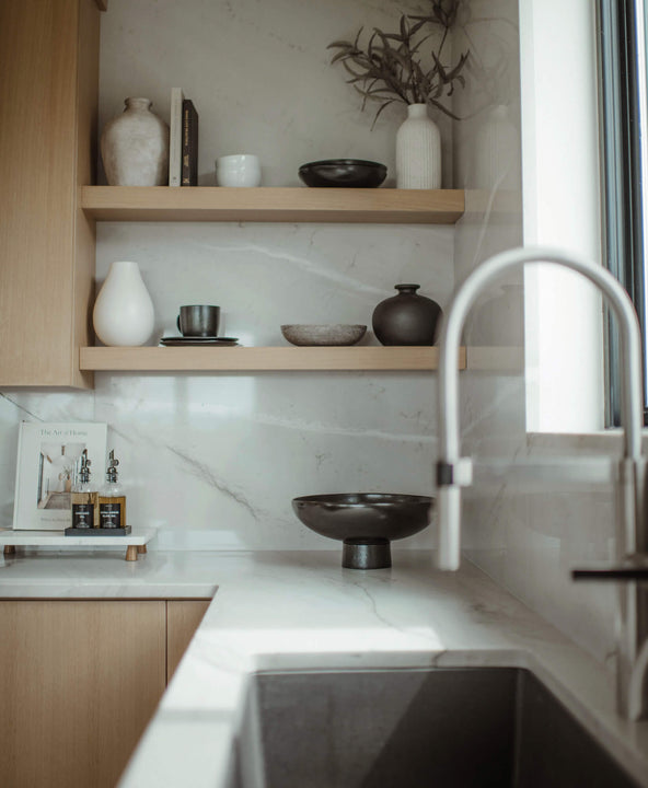 White oak floating shelves in a kitchen made entirely from white oak. The shelves are styled with various vases, books, and other elements.