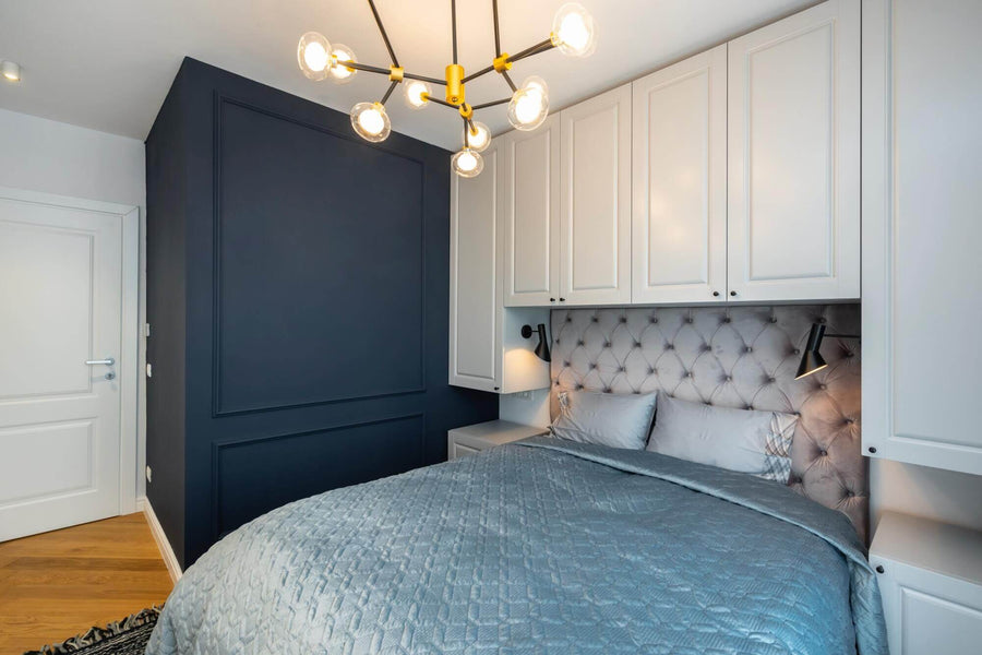 A blue bedroom with white cabinets and herringbone wood flooring.