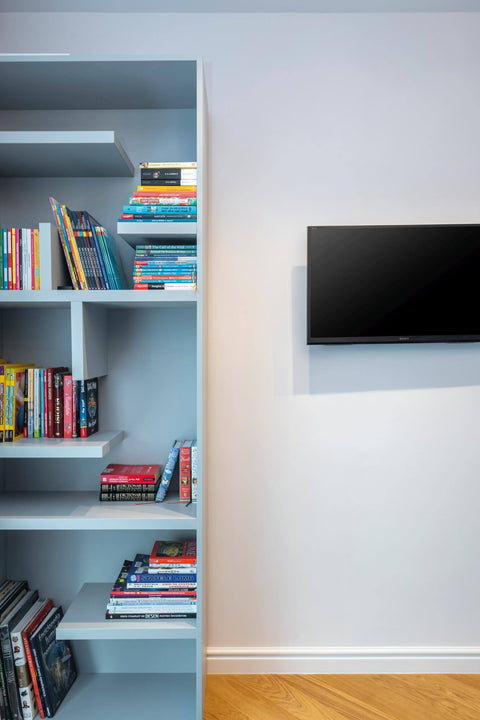 Blue bookshelf on herringbone wood floor.