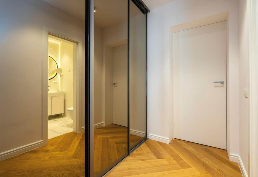 Herringbone wood floors in a hallway with mirrors.