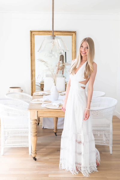 A woman standing in front of a dining table set on hardwood flooring