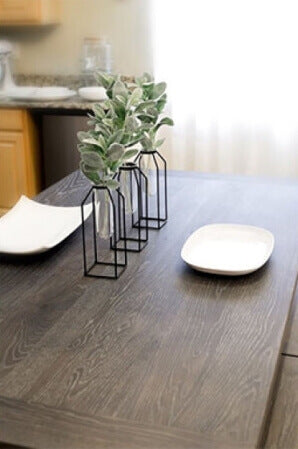 Farmhouse table top with dark wood and 2 place settings on it.