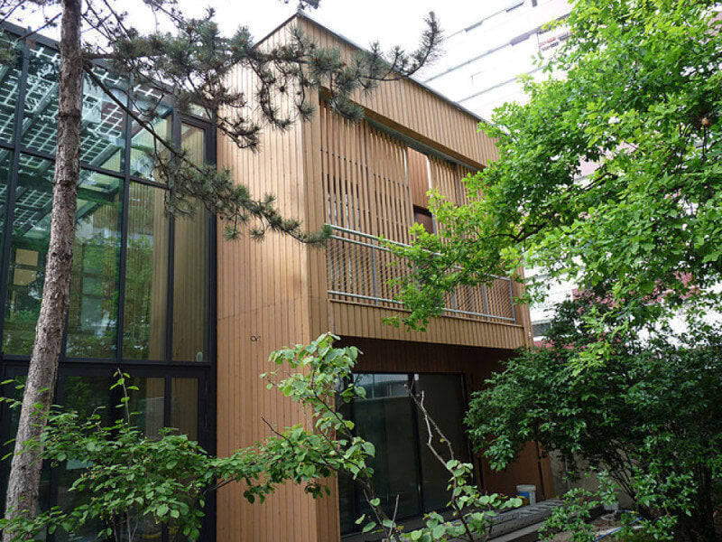 The exterior of a bed and breakfast that has wood cladding finished with an exterior wood oil and trees growing around the exterior.