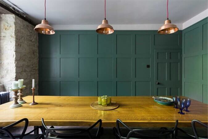 Live edge dining table in a room with paneled teal walls.