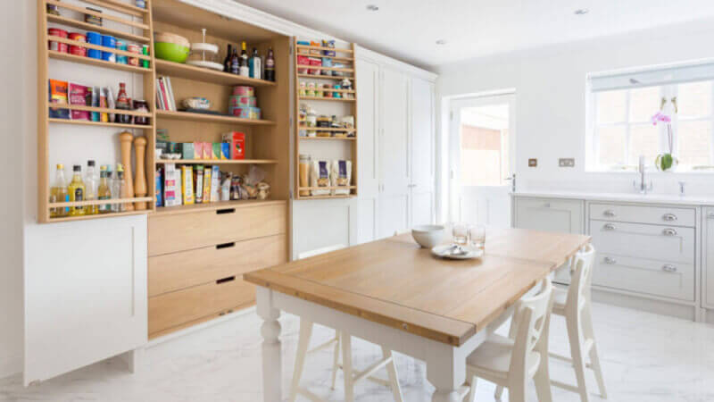 A beautifully redesigned shaker kitchen that takes advantage of natural light, fitted with natural wood shelving.