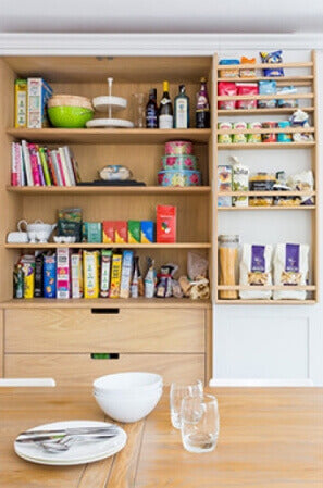 Wood pantry shelving in a white shaker kitchen cabinet.