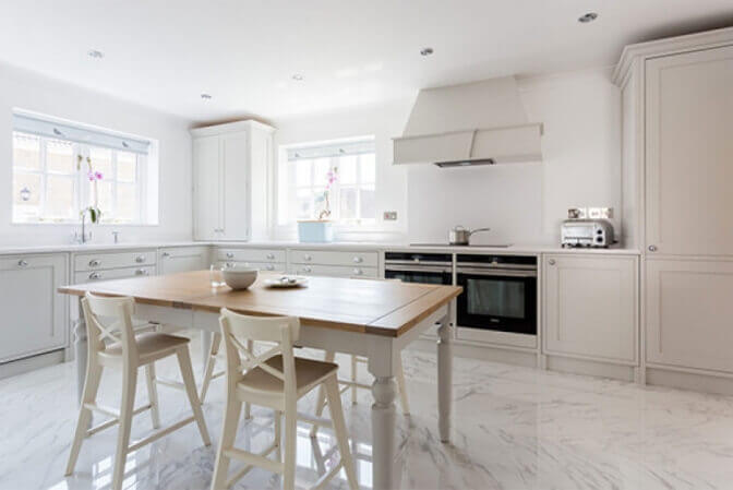 White shaker kitchen with dining table in the middle.