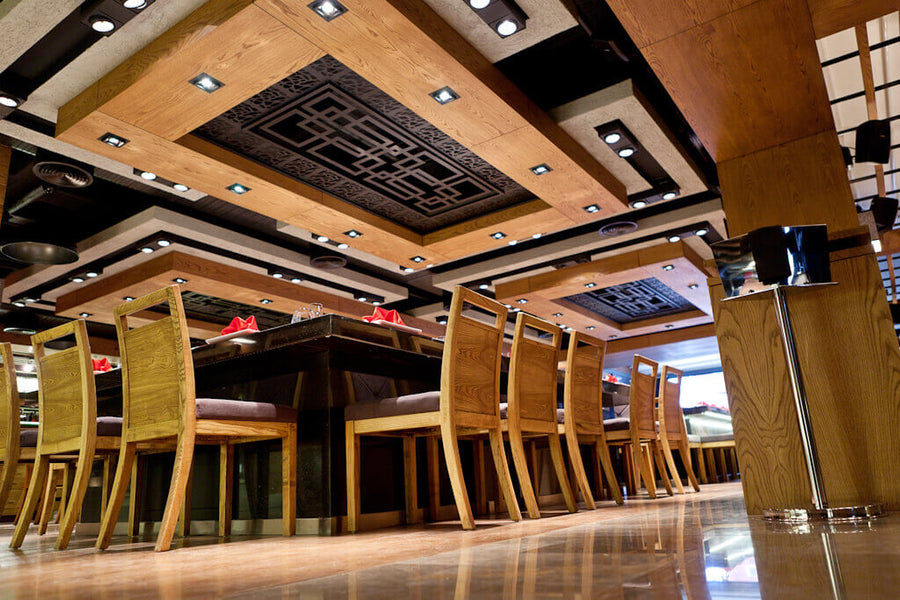 The ceiling in an asian restaurant has large wood panels and lighting.