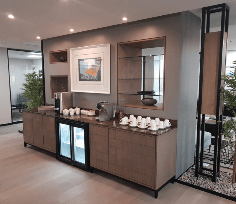 A shared office that has a stocked kitchen area with wood cabinets finished using Rubio Monocoat hardwax oil wood finish.