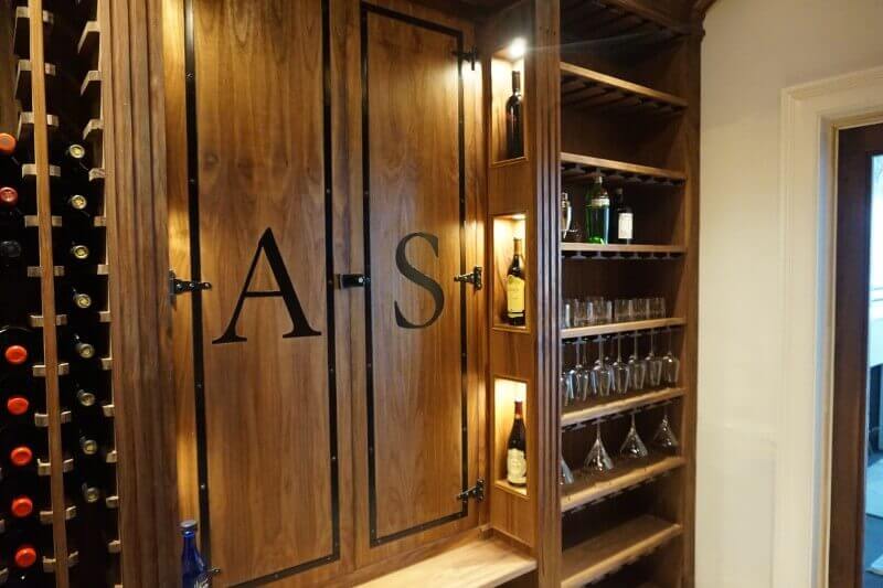 Walk-in walnut liquor cabinet with matte wood finish.