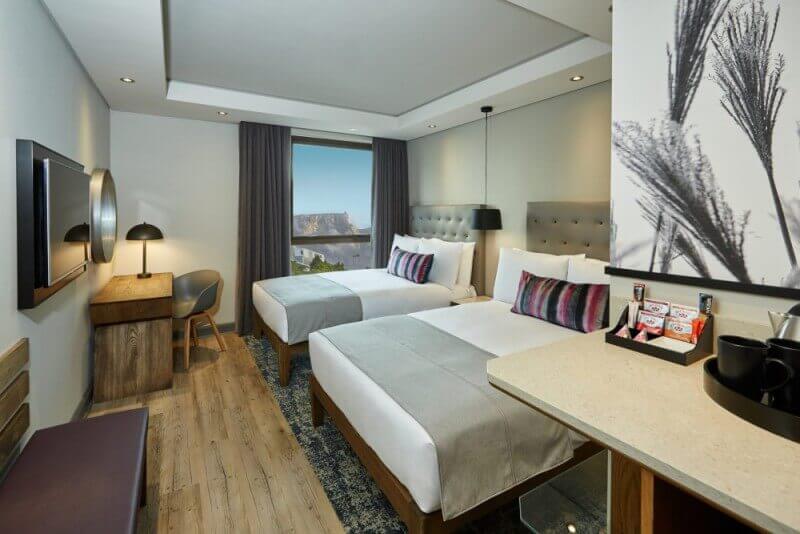 A hotel bedroom with wood flooring.