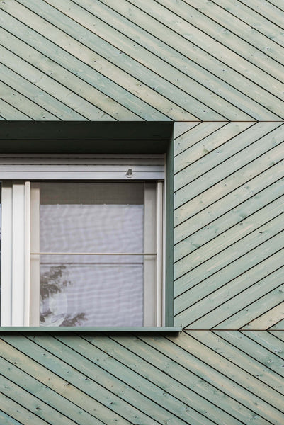 A closer view of chevron wood siding finished with a green exterior wood finish.