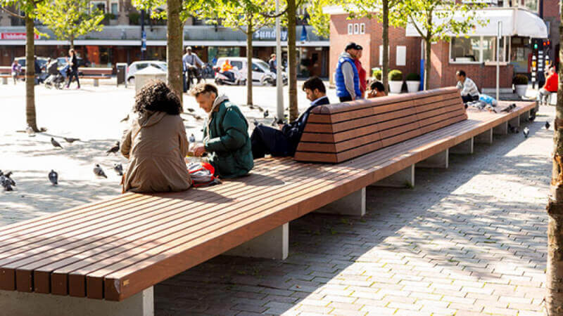 A wooden park bench with people sitting on the side.